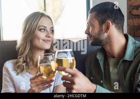 Fröhliches Paar, das Weingläser anklimmte und sich im Restaurant ansah Stockfoto