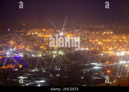 Nächtliche Lichter der Stadt. Verwischen Sie Hintergrund und helle Sterne aufgrund der Objektivfunktionen. Stockfoto