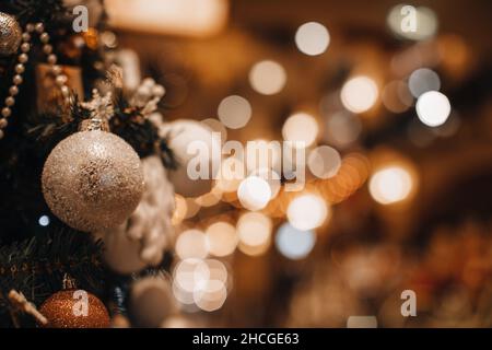 Weihnachtskugel mit silbernem Glitter, der an den Zweigen des Weihnachtsbaums hängt. Winterurlaub Feen Girlanden Beleuchtung und festliche magische Details in der Stockfoto