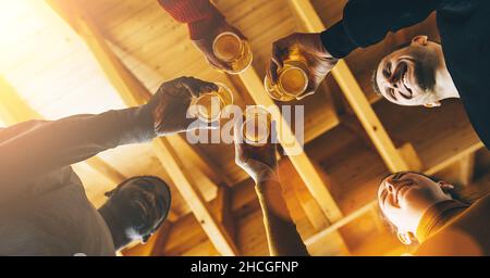 Multirassische Gruppe von Freunden genießen ein Bier, junge Menschen Hände Toasten und jubeln Aperitif Bier halb Pint in der Bar oder Brauerei englischen Pub, Freunde Stockfoto