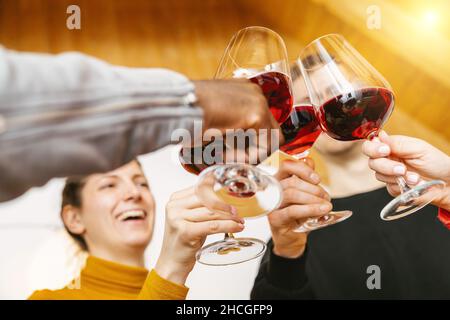 Freunde toasten Rotweinglas und haben Spaß jubeln mit Weinprobe - Junge Menschen genießen Zeit zu Hause - Jugend und Freundschaft Co Stockfoto