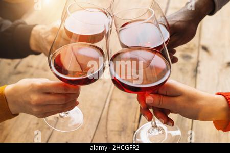 Hände toasten Rotweinglas und Freunde, die Spaß haben, bei Weinprobe-Erlebnis jubeln - Junge Menschen genießen Zeit zusammen bei Weinprobe - Yo Stockfoto