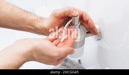 Hände mit dem Spender für die Reinigungshanddesinfektionslösung für die Gelpumpe. Klares Desinfektionsmittel in der Pumpflasche zum Abtöten von Keimen, Bakterien und Viren. Stockfoto