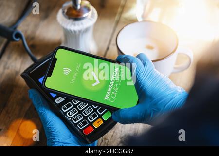 Kontaktloses Bezahlen auf einem Mobiltelefon. Nahaufnahme einer Frau, die mit einer Smartphone-Bildschirm-Anwendung kontaktlos in der Hand zahlt. Smart-Gerät mit Handhaltung Stockfoto