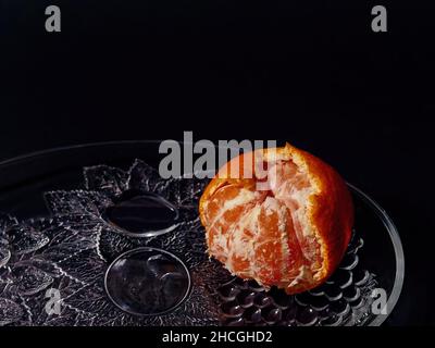 Nahaufnahme einer halbgeschälten Mandarinorange auf schwarzem Hintergrund Stockfoto
