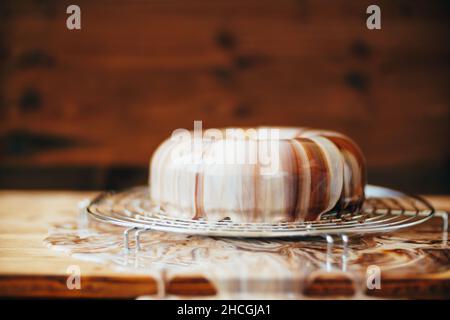 Mousse Cake mit Spiegelvereisung befindet sich auf einem Metallständer auf dem Tisch Stockfoto