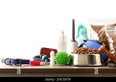 Futter und Zubehör für Spaziergang, Spiel und Körperpflege für den Hund auf Holztisch isolierter Hintergrund Vorderansicht. Horizontale Zusammensetzung. Stockfoto