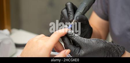 Manikurist entfernt Nagellack nutzt die elektrische Maschine der Nagelfeile während der Maniküre in einem Nagelstudio Stockfoto