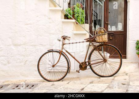 Ein altes, rostiges Fahrrad, das als Dekoration mit Blumenkorb vor einem Haus diente Stockfoto