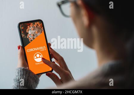 Coronavirus-Tracking-App auf einem mobilen Smartphone. Nahaufnahme einer Frau, die Menschenmengen in einer Smartphone-Bildschirm-Anwendung verfolgt. Hand halten Smart dev Stockfoto