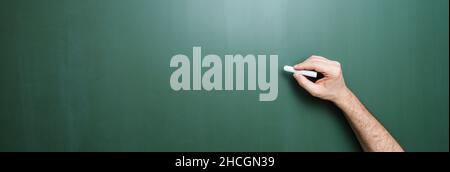 Die Hand beginnt mit Kreide auf eine saubere Tafel zu schreiben Stockfoto