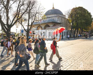 Viele Touristen, die in Sultanahmet die Straße entlang gehen, mit einer Führerin vor dem Hotel, die einen roten Regenschirm in der Hand hält. Konzept von Tourismus und Attraktionen in ist Stockfoto