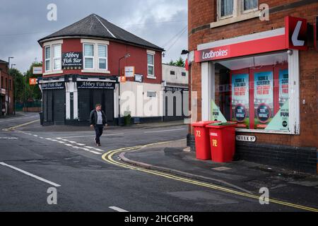 Eine Straßenszene in einer Innenstadt von Derby mit einem Fisch- und Chipshop und einem Wettshop an den Straßenecken, Derby, England Stockfoto