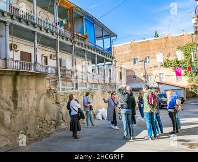 Weibliche Reiseleiterin zeigt alte Nachbarschaftsgebäude in Tiflis. Tourismus und kostenlose Wanderungen in Sakartvelo (Georgien). 03.03.2020. Stockfoto