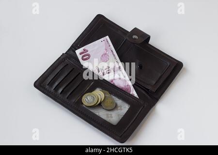 Nur die türkischen zehn Liras und Münzen sind in braunem Leder-Damengeldbeutel auf weißem Hintergrund. Stockfoto