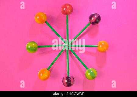 Leckere Lutscher auf rosa Pastellfarben Hintergrund. Set von realistischen bunten Lutschern auf grünen Plastikstiften. Sommer- und Pop-Art-Konzept. Draufsicht. R Stockfoto