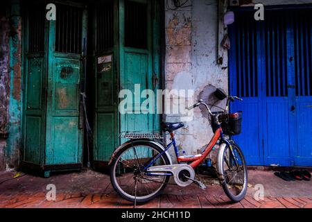 In einem alten, baufälligen Gebäude in einer engen Gasse in Bangkoks Chinatown, Thailand, wird ein Fahrrad geparkt Stockfoto