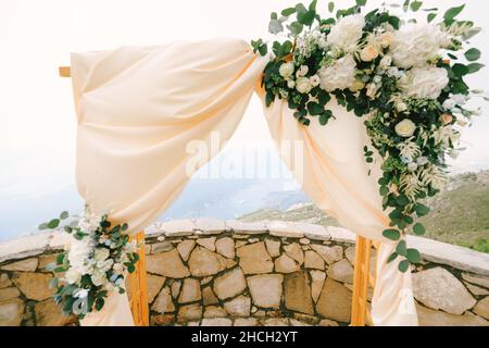 Rechteckiger Holzbogen mit Satin, Blumen und grünen Blättern Stockfoto