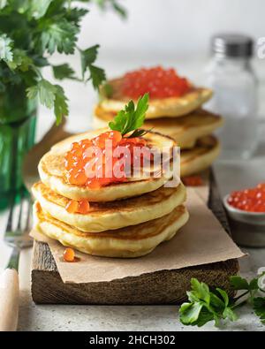 Pfannkuchen mit rotem KaviarPfannkuchen mit rotem Kaviar auf einem Holzbrett serviert. Ein klassisches Gericht für den Urlaub in Maslenitsa Stockfoto