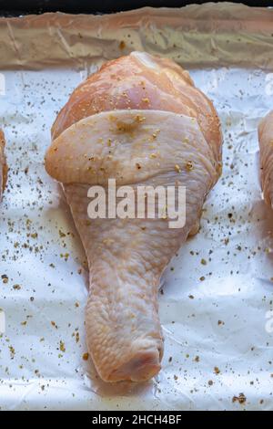 Vertikales Foto von rohen Hähnchenbeinen auf Aluminiumfolie Stockfoto