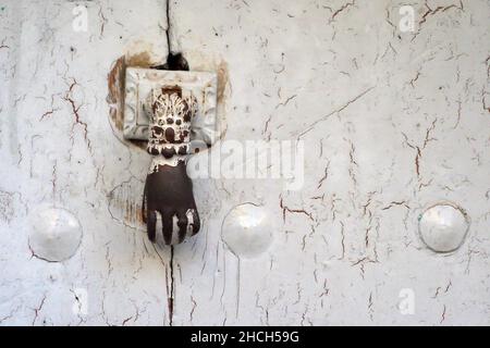 Eiserner Türklopfer als Hand auf weißer Holztür Stockfoto