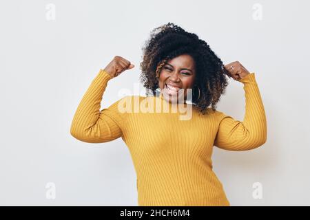 Fröhliche starke Frau, die Muskeln vor weißem Hintergrund beugt Stockfoto