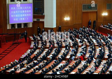 (211229) -- PEKING, 29. Dezember 2021 (Xinhua) -- Die Abgeordneten des Nationalen Volkskongresses 13th (NPC) stimmen mit überwältigender Mehrheit der Entscheidung des NPC über die Verbesserung des Wahlsystems der Sonderverwaltungsregion Hongkong (HKSAR) bei der Abschlusssitzung der vierten Sitzung des NPC 13th in der Großen Halle des Volkes in Peking zu. Capital of China, 11. März 2021. Xinhuas Top-10-Nachrichtenereignisse in China im Jahr 2021 3. Das Wahlsystem Hongkongs ist verbessert Am 11. März verabschiedete Chinas oberste Legislaturperiode einen Beschluss zur Verbesserung des Wahlsystems der Sonderverwaltung von Hongkong Stockfoto