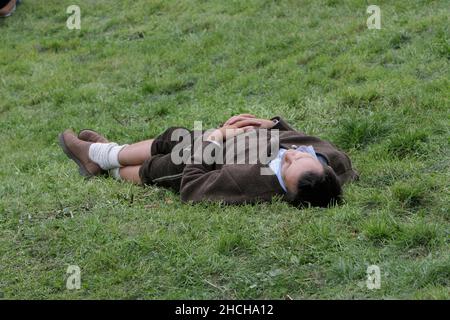 Junger Mann in bayerischer Tracht schläft vom Oktoberfest auf Rasen, Bierleiche, Wiesn, München, Bayern, Deutschland Stockfoto