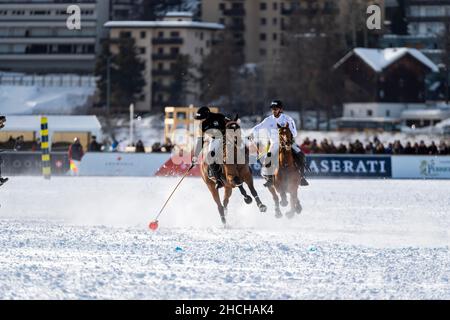 NIC Roldan (schwarz) vom Team Badrutt's Palace Hotel führt den Ball an, verfolgt von Kutlay Yaprak (weiß) vom Team Maserati, 36th Snow Polo World Cup St. Stockfoto