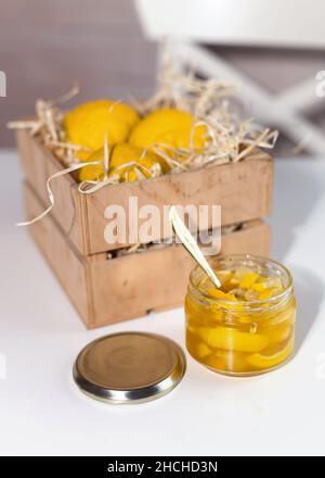 Glas mit Yuzu Marmelade in der Nähe einer Holzkiste mit gelben Zitrusfrüchten Yuzu Frucht. yuja-cheong ist Marmelade aus Yuzu-Schale, Saft und Honig hergestellt. Stockfoto