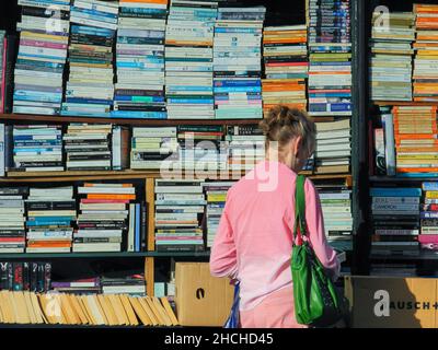 Eine ältere Frau, die vor dem Hurlingham Bookshop, Ranelagh Gardens, Fulham High Street, London, SW6, ein Buch liest, GROSSBRITANNIEN Stockfoto