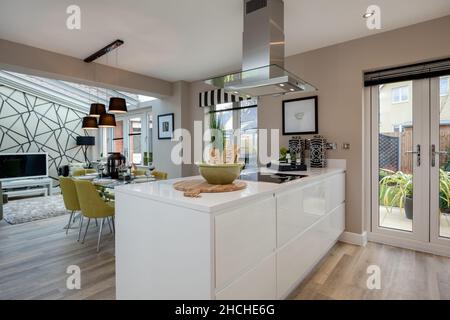 Kentford, Suffolk, England - Feb 25 2016: Komplett eingerichtete offene Luxusküche und Esszimmer mit Einbauschränken und Geräten, Place Set gla Stockfoto