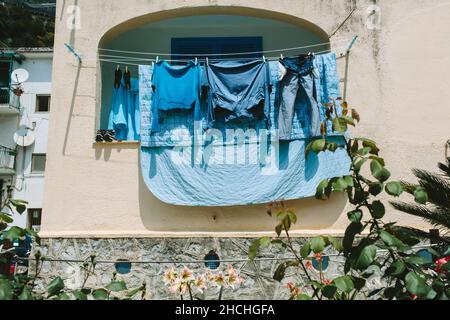 Aus dem niedrigen Winkel gedrehte blaue Wäsche, die an den Linien auf dem Balkon hängt Stockfoto