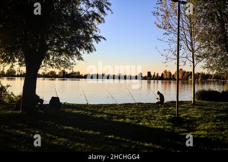 Fischer am Flussufer bei Dämmerung im Herbst Stockfoto