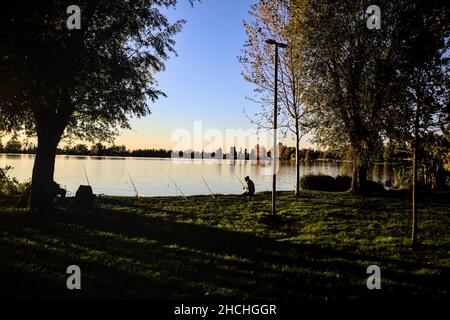 Fischer am Flussufer bei Dämmerung im Herbst Stockfoto