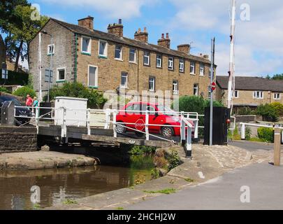 Schwingt eine Brücke mit einem roten Auto, das den Thanet Canal oder den Spring Branch des Leeds und Liverpool Canal von Skipton nach Skipton Castle überquert. Stockfoto