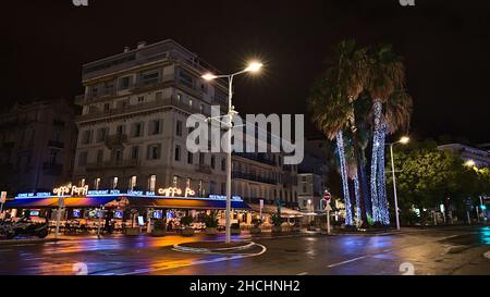 Schöne Nachtansicht der Innenstadt von Cannes, an der französischen Riviera, Frankreich mit Caffe Roma und Lichtern, die sich auf der nassen Straße spiegeln. Stockfoto