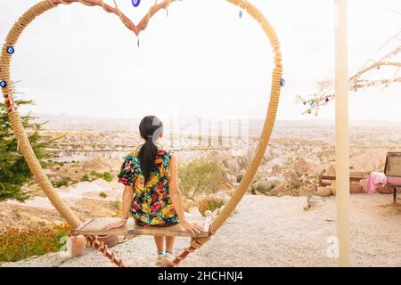 Verträumte kaukasische Mädchen auf berühmten Cappadocia Schaukeln genießen Sonnenuntergang in der Türkei Stockfoto