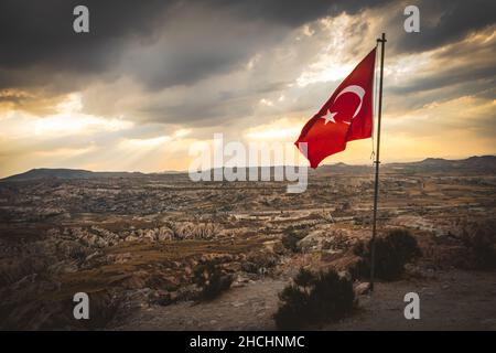 Nationales Türkei-Symbol - türkische Flagge auf einem Posten auf einem Hügel über den Kappadokien-Tälern mit dramatischer Kopie-Weltraumwolkenlandschaft Stockfoto