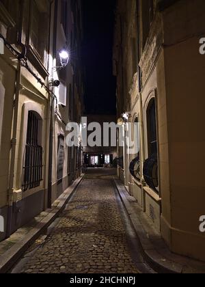 Schöne Nachtansicht der engen Gasse im historischen Zentrum von Avignon, Provence, Frankreich mit Straßenlaterne, Kopfsteinpflaster und historischen Gebäuden. Stockfoto