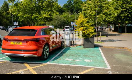 Loch Lomond, Schottland - Juli 25th 2021: Rotes Audi e-tron Elektrofahrzeug lädt an einer Station auf einem Parkplatz Stockfoto