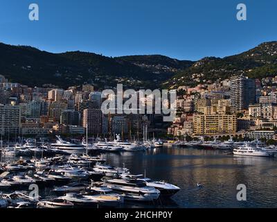 Wunderschönes Stadtbild des Fürstentums Monaco bei nachmittäglicher Sonneneinstrahlung mit Jachtbooten, die im Hafen Hercules und in Hochhäusern festgemacht sind. Stockfoto