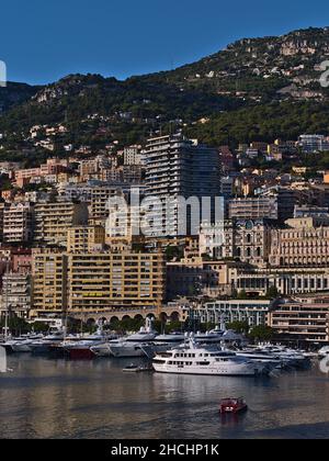 Schöner Blick auf das Fürstentum Monaco in der Nachmittagssonne mit Wohnhochhäusern und dem Yachthafen Port Hercule mit Anlegeyachten. Stockfoto