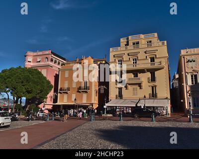 Blick auf historische Gebäude mit bunten Fassaden im Stadtteil Monaco-Ville in der Nachmittagssonne mit Touristen und Souvenirläden in Monaco. Stockfoto