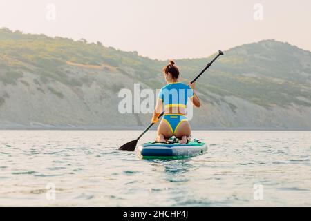 4. August 2021. Anapa, Russland. Sportliche Frau, die auf dem Stand Up Paddle Board in Black Sea schwimmt. Frau Urlaub auf Red paddel supboard im Meer. Stockfoto