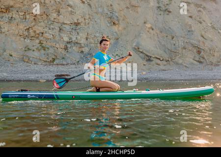 4. August 2021. Anapa, Russland. Sportliche Frau, die auf dem Stand Up Paddle Board in Black Sea schwimmt. Frau Urlaub auf Red paddel supboard im Meer. Stockfoto