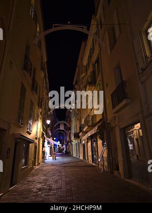 Nachtansicht mit abnehmender Perspektive der schmalen Gasse im alten Stadtteil Monaco-Ville am Abend mit historischen Gebäuden in Monaco, Französische Riviera. Stockfoto