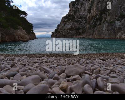 Blick auf die beliebte Bucht Calanque d'en-Vau im Nationalpark Calanques in der Nähe von Cassis, Französische Riviera am mittelmeer mit runden Steinen am Strand. Stockfoto