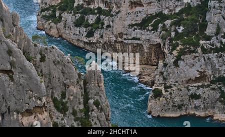 Luftaufnahme der schmalen Bucht Calanque d'en-Vau an der mittelmeerküste bei Cassis, Französische Riviera, umgeben von den schroffen Klippen der Calanques. Stockfoto