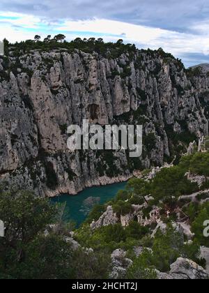 Blick auf die zerklüfteten Klippen des Massif des Calanques in der Nähe von Cassis, Französische Riviera am mittelmeer mit Pinien und enger Bucht. Stockfoto